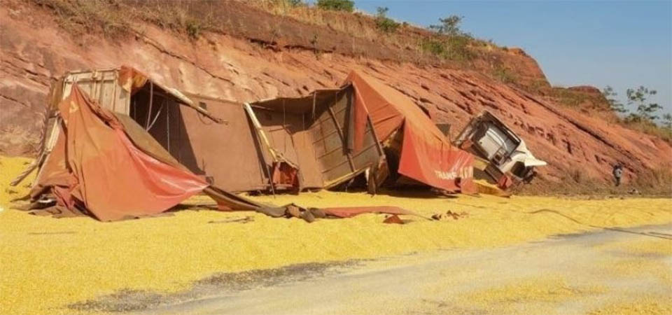 Carreta com milho tomba em serra e mata motorista